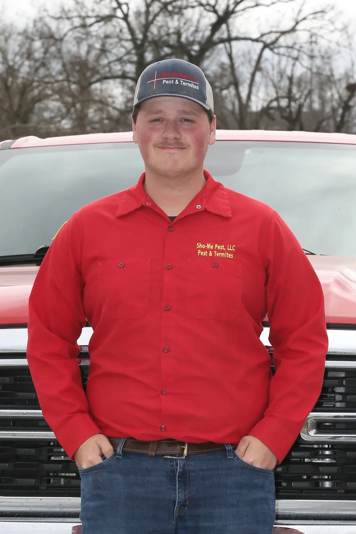 Man in red shirt standing by truck.