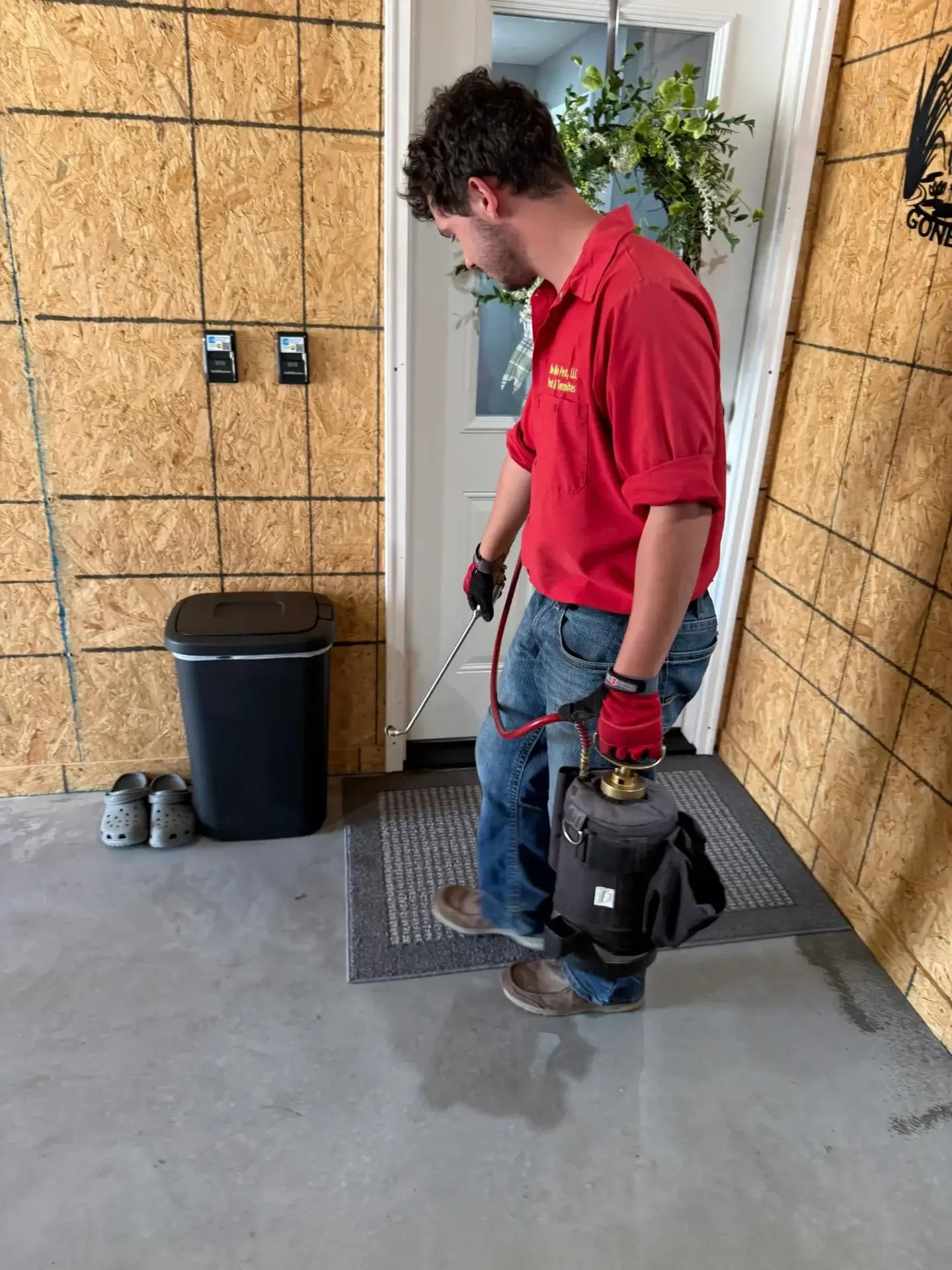 Person spraying pesticide near a door entrance.