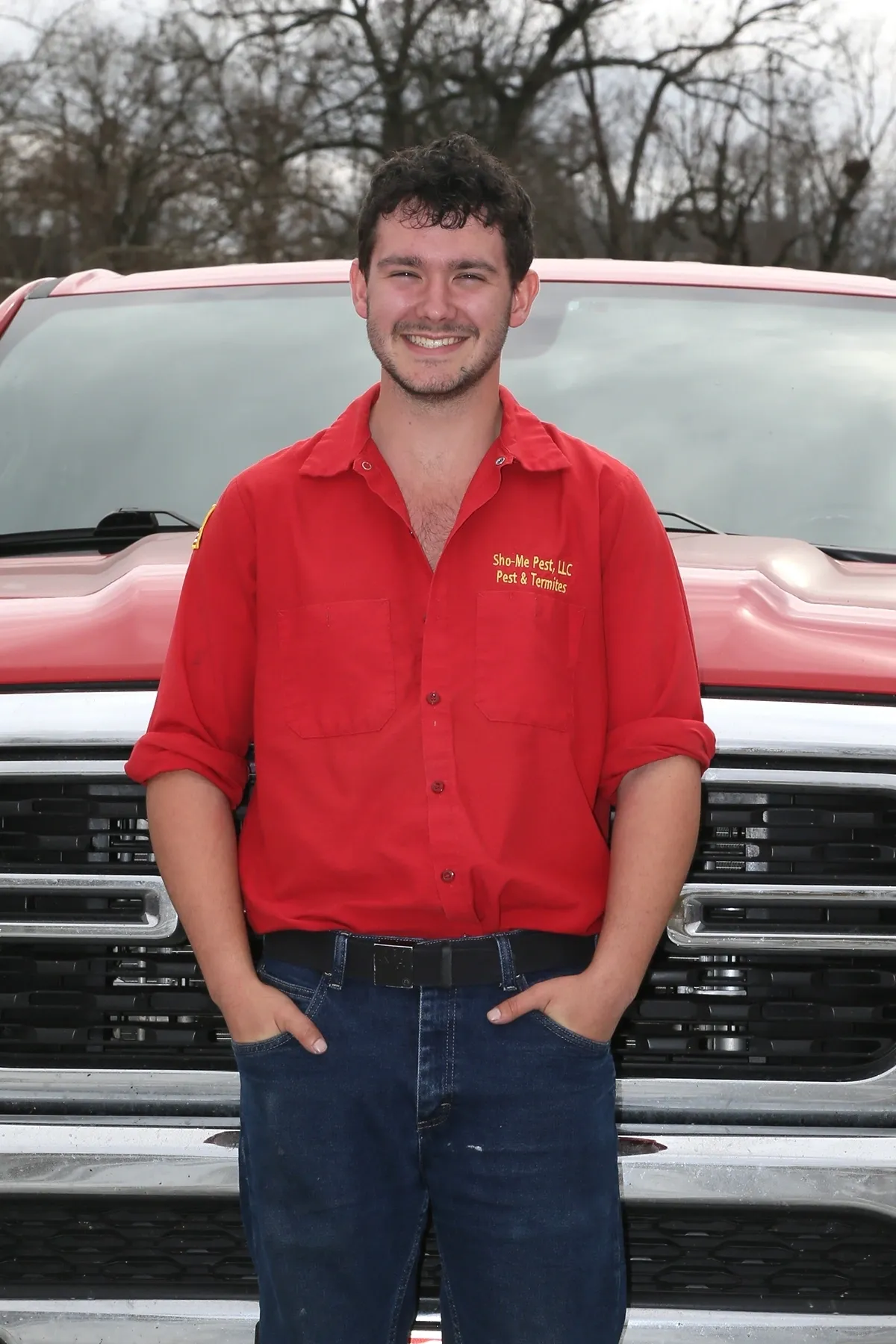 Man in red shirt standing by truck.
