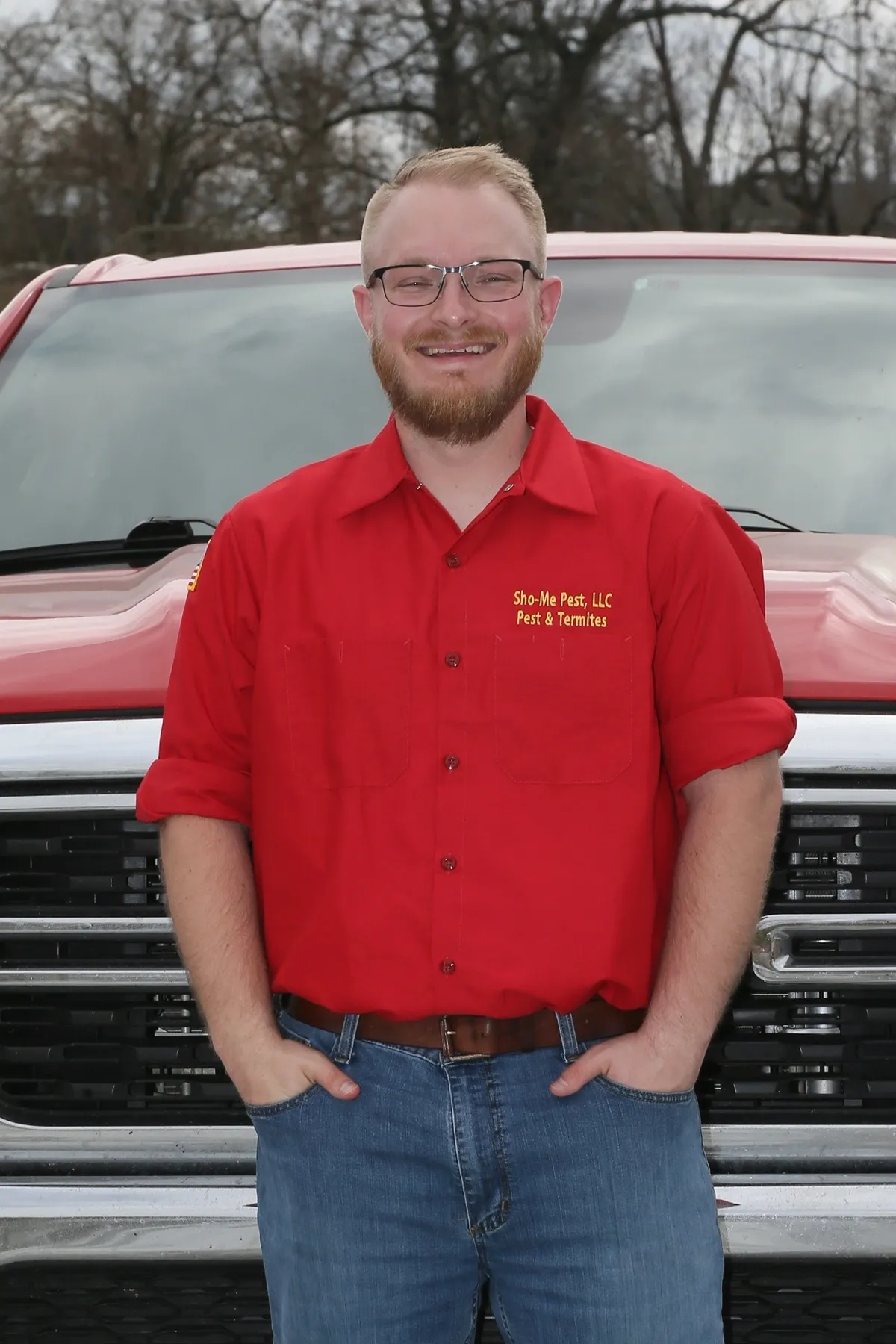 Man in red shirt standing by truck.